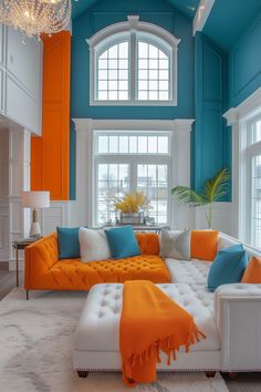 an orange and blue living room with white furniture, chandelier and large windows