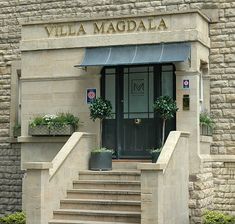 the front entrance to villa maddala with potted plants and stairs leading up to it