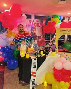 a man standing next to a table filled with balloons