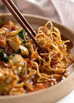 a bowl filled with noodles, vegetables and chopsticks