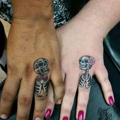 two people with matching tattoos on their hands, one has a skull and the other has a flower