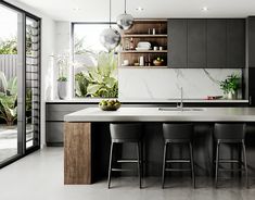 a kitchen with black cabinets and white marble counter tops, two bar stools at the center