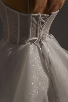 the back of a white wedding dress with silver sequins on it's waist