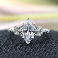 an engagement ring with a pear shaped cut diamond in the center, surrounded by diamonds