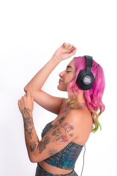 a woman with pink hair is wearing headphones and has tattoos on her arms, shoulder and arm