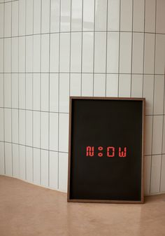 the word wow written in red on a black framed poster next to a white tiled wall