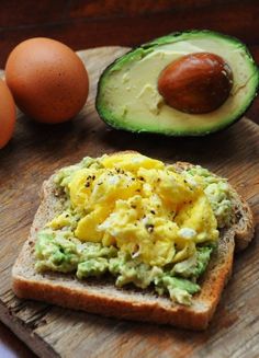 an avocado and egg sandwich is on a wooden cutting board