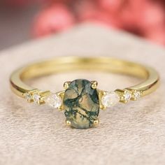 a close up view of a ring with a green stone and three diamonds on it