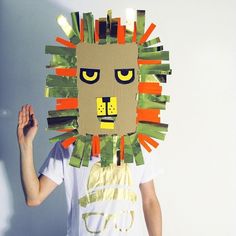 a person wearing a paper lion mask made out of strips of green and orange tape