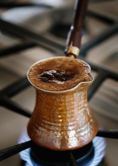 a brown pitcher sitting on top of a stove with a wooden stick sticking out of it