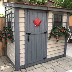 an outdoor storage shed with potted plants on the side and a canadian flag painted on the door