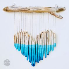 a group of blue and white sticks hanging from a wooden stick on a wall next to driftwood