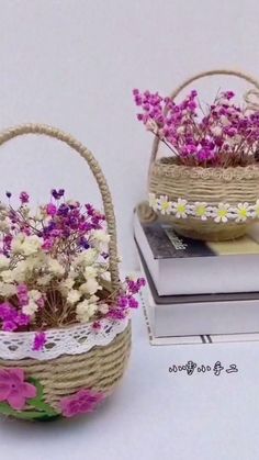 two baskets filled with flowers sitting on top of a white table next to a stack of books