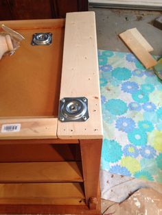 a wooden table with two metal knobs on it's top and a blue flowered blanket in the background