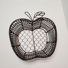 an apple made out of chicken wire on a white surface