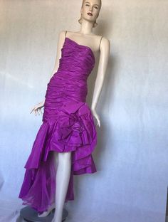 Vtg late 80s Victor Costa stunning Purple ruched asymmetrical bodycon ball gown 8S Preowned. Condition. 10/10. No issues. No signs of wear. A stunning couture ball gown or special occasion dress. Purple acetate, rear zipper, fully lined, this dress is a masterpiece of engineering. Extensive ruching in the boned figure hugging bodice, swathes of extra fabric gather falls from the diagonal waist one side accentuating the hip with a huge fabric rosette, bow and on the other side, an asymmetrical cu Asymmetrical Party Evening Dress With Ruched Bodice, Asymmetrical Evening Dress With Ruched Bodice For Party, Fitted Ruched Evening Dress, One Shoulder Ruched Fitted Gown, Cocktail Gown With Ruched Fitted Bodice, Purple Fitted One-shoulder Gown, Fitted One-shoulder Purple Gown, Fitted Asymmetrical Pre-draped Evening Dress, Fitted Ruched Evening Dress For Party Season