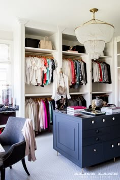 an organized closet with clothes and handbags hanging on the walls, along with a chandelier