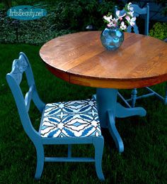 a wooden table and two blue chairs in the grass