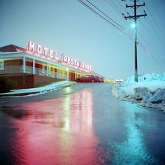 a motel that is on the side of a road with snow and ice around it