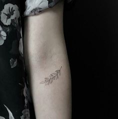 a woman's arm with a small flower tattoo on the left side of her arm