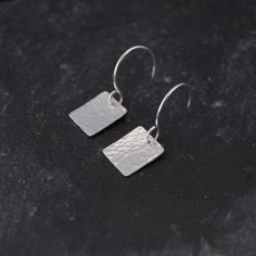 "Small Square Silver Earrings, have been made using sterling silver which has been hammered with a dimpled texture.  They are finished with sterling silver fish hook ear wires.  These small square earrings are an elegant yet simple pair of earrings which are perfect for evening or casual wear.  >Materials - Sterling silver >Measurements - 1.2 cm (0.5\") long by 1 cm (0.4\") wide, with a drop of 2.5 cm (1\") from the top of the ear wire >Care Instructions - Sterling silver can be polished with a silver polishing cloth to maintain its shine >More Hammered Earrings - http://etsy.me/1n1Asjv" Dainty Hammered Sterling Silver Earrings, Minimalist Silver Hammered Earrings, Silver Square Metal Earrings, Silver Hammered Rectangular Earrings, Silver Sterling Silver Square Pendant Earrings, Simple Silver Earrings, Hammered Earrings, Hammered Sterling Silver, Square Earrings