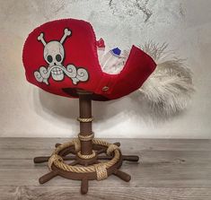 a red pirate hat with a skull and crossbones on it sitting on a wooden chair