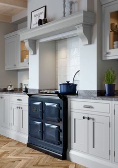 a kitchen with white cabinets and an old fashioned stove in the center, surrounded by wood flooring