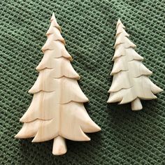 two wooden christmas trees sitting on top of a green surface