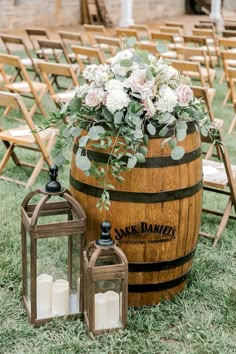 a wooden barrel with flowers and candles on the grass next to it is an aisle