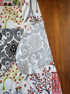 two pieces of fabric sitting on top of a wooden floor next to a table cloth with an image of the eiffel tower