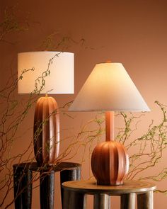 two vases sitting on top of a table next to a lamp with a white shade