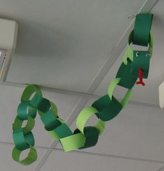 a green snake hanging from the ceiling with some tape on it's head and mouth