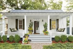 a white house with two porches and plants on the front