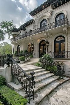 a large white house with black iron railings and stairs leading up to the front door