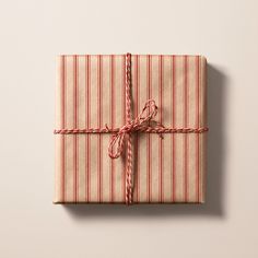 a wrapped gift box with red and white striped wrapping paper tied up to it's side