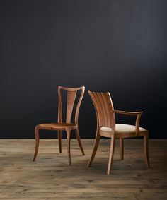 two wooden chairs sitting next to each other on top of a hard wood floored floor