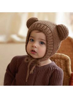 a small child wearing a knitted bear hat