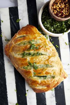 a loaf of bread sitting on top of a table next to a bowl of greens