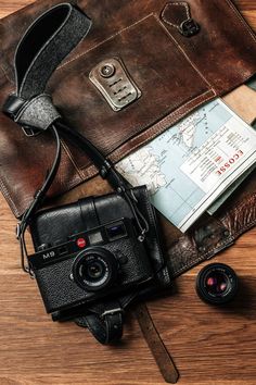 an old camera sitting on top of a leather bag