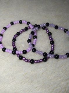 Perfect for a fan of purple!! Lots of purple!! Lightweight and super comfy, these are great for just a casual splash of color to any outfit. Made with glass beads (that's the purple) and plastic (that's the black), they're just cute and fun to have on! Each bracelet CAN vary in size due to the glass beads being variable sizes, but they measure approximately 18-19cms. They are made with .5mm elastic cord and just a little wee touch of jewelry glue to get that knot nice and SECURE! Because we can' Purple And Black Bracelet, Trendy Black Beaded Bracelets, Trendy Purple Plastic Jewelry, Handmade Casual Purple Bracelets, Casual Purple Handmade Bracelets, Casual Handmade Purple Bracelets, Purple Beaded Bracelets With Black Beads As A Gift, Trendy Black Plastic Bracelets, Handmade Black Plastic Jewelry