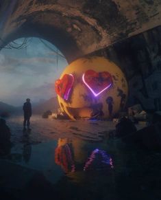 two people standing in front of a large heart shaped object with neon lights on it