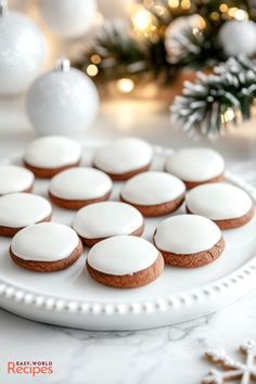 cookies with white icing on a plate next to christmas decorations and baubles