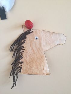 a wooden horse head mounted to the wall with a red button on it's nose