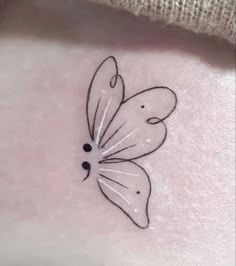 a small butterfly tattoo on the back of a woman's stomach, with black dots