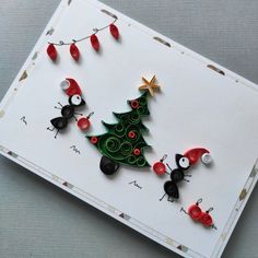 a christmas tree made out of buttons on top of a white card with red and black pins