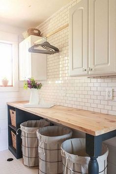 three buckets sitting on top of a wooden counter in a kitchen next to white cabinets