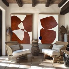 two abstract paintings hang on the wall next to chairs and vases in a living room