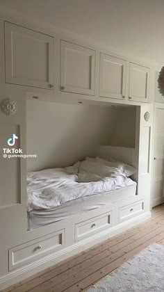 there is a bunk bed built into the wall in this room with white cupboards