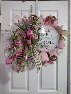 a pink and green wreath hanging on a door with the words, home sweet home