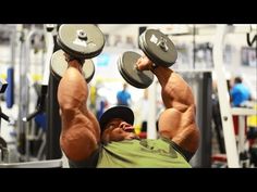 a man lifting two dumbs in a gym